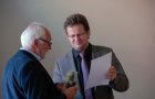 Schuldezernent Thomas Brederlow berreicht eine Flasche Wein und die Urkunde